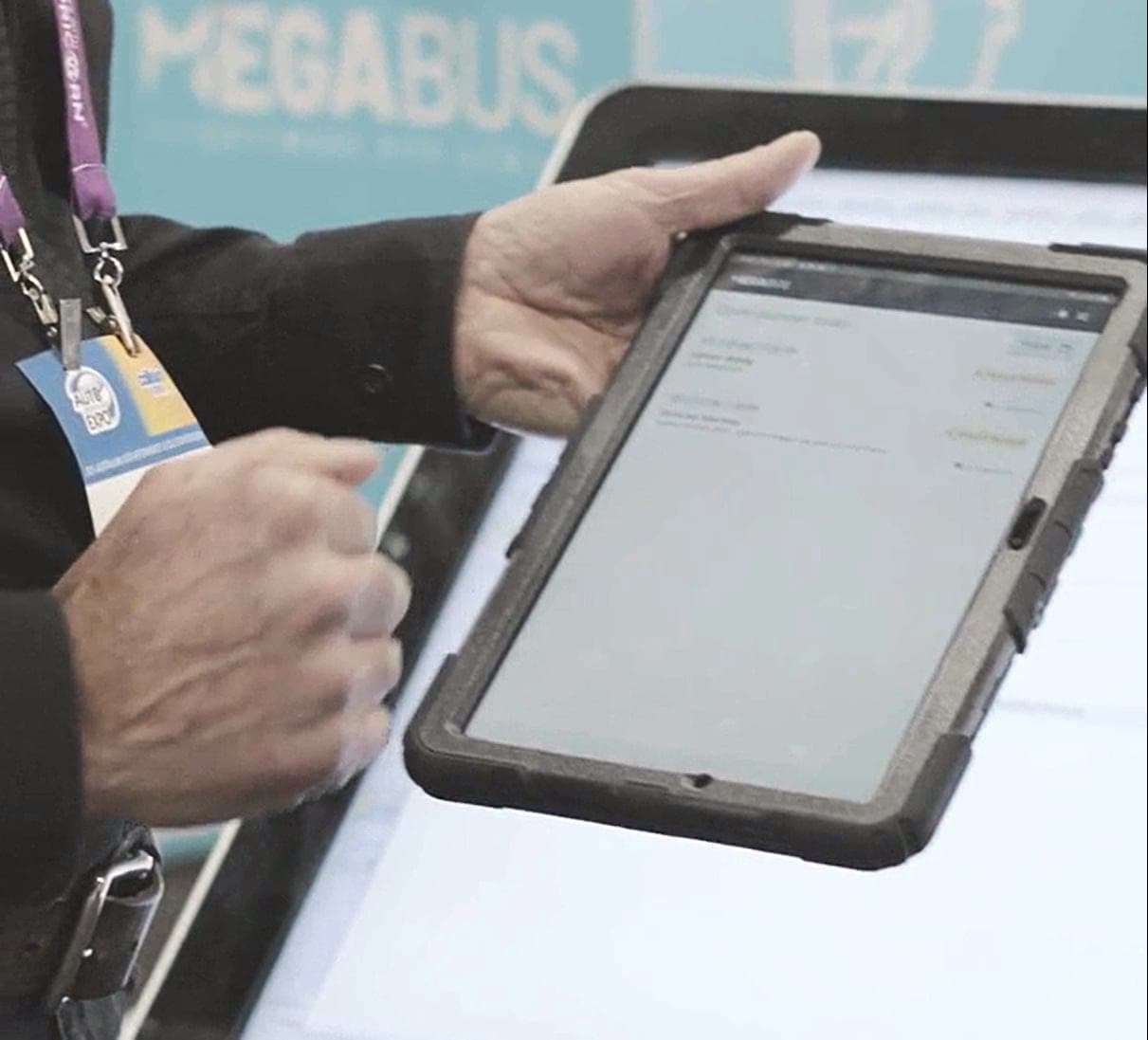 Hands holding a rugged tablet at a Megabus stand
